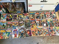 Overview of all 30 vintage comics including Hex, Kull, Jonah Hex, and others, laid out on a wooden surface for identification.