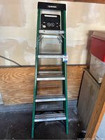 Full view of the 6-foot green Husky step ladder showing metal steps, side rails, and black top tray.