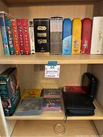 Shelf with boxed DVD sets of Friends seasons 1, 2, 3, 4, 10 and Star Wars Special Edition Trilogy boxed VHS and DVDs including Empire Strikes Back and Return of the Jedi. Also includes boxed collectible CD and DVD sets.