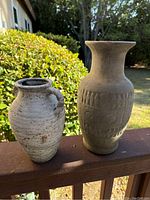 Photo showing two ceramic vases outdoors on a ledge, demonstrating their shape, size, and exterior condition.