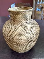 Front view of the vintage hand woven urn shaped basket showing its size and textured weave detail.