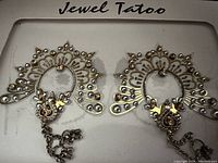 Close-up of a pair of gold and silver stick-on body tattoos with crystal details.