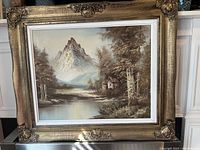 Framed original oil painting showing mountain and river landscape in neutral brown and beige tones.