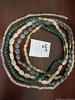 Five gemstone bead necklaces arranged in a circle, showing variety in bead shape, size, and color.