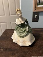 Front view of the Royal Doulton 'Soire' figurine showing a woman in a green and cream dress holding a fan