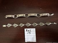 Top view of two silver filigree bracelets laid out on dark surface, showing overall design and structure.