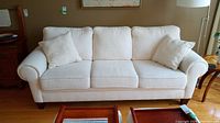 Front view of cream/beige sofa with three seat cushions and two throw pillows