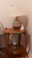Full view of oak end table with lamp, figurine, and clock on and below the table