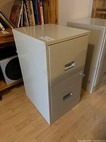 Side and top angled view of the beige two-drawer filing cabinet showing its height and depth with the lock on the top drawer visible.