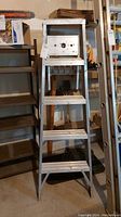 Front view of the full 5-foot aluminum step ladder showing five steps and top platform with cutouts.