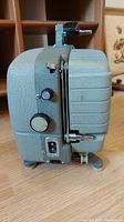 Side profile of the gray textured Sekonic 8mm movie projector showing power socket, control knobs, and mounting screws