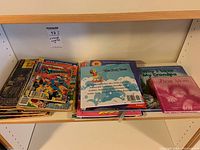Photo of shelf with a stack of vintage comics and children's books, including Archie comics and other titles.
