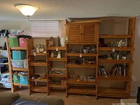 Wide angle view of the wooden shelving unit showing five distinct sections, one with a cupboard. Items on shelves are not part of the lot.