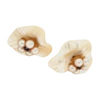 Close-up photo of Mother of Pearl earring jackets showing their irregular wavy shape and cream-colored reflective surface with embedded cultured pearls.