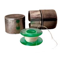 Antique sterling silver bobbin case with a plastic bobbin (not included in lot). The case shows tarnish and wear.