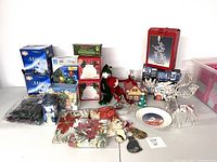 Full lot of Christmas items including string lights, figurines, and ornaments arranged together on floor against white wall.