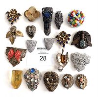 Full lot of 17 vintage dress clips arranged on white background showing various floral, beaded, and metal designs in assorted colors and finishes