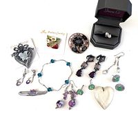 Overview of multiple jewelry pieces including earrings, brooches, bracelet, and pendant arranged and photographed together.
