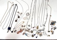 Overview of assorted necklaces, earrings, and pins including colorful stones and metal decorations on a white background.