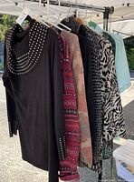 Six ladies tops on hangers showing varied colors and patterns.