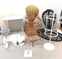 Overall view of all vintage retail display items on a gray table against white background, showing the woven mannequin heads, photo box, copper earring stand, white earring holders and hands.
