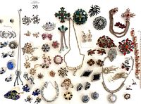 Top-down view showing a variety of vintage rhinestone jewelry including brooches, earrings, and necklaces.