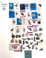 Top-down photo showing the full lot of vintage charms with some on original cards, arranged on a white background.