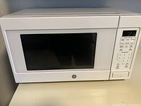 Closed view of the white GE microwave oven showing front door with black window and control panel on the right.