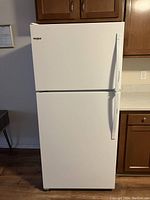 Front view of white Whirlpool top-freezer refrigerator showing overall exterior condition.