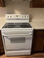 Front view of white Frigidaire electric stove with smooth glass cooktop and oven door with window and handle.
