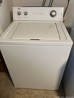 Front view of white Roper top load washer showing top lid and control panel with dials and selector options.