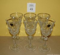 Set of six Capri crystal stemware glasses arranged against a yellow background. Each glass has a decorative cut pattern and a starburst base. Four glasses visible with the original Capri Crystal label on some.