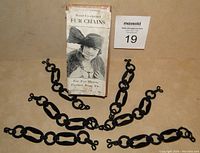 Photo of six black hand crocheted fur chains displayed in front of their original vintage box labeled 'Hand Crocheted Fur Chains'.