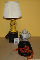 Full lot showing yellow glaze lamp with pleated shade, porcelain lidded pot, black carved dish, and two strings of prayer beads.