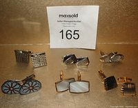 Photo showing six pairs of vintage 1960s cufflinks arranged in two rows on a neutral background, each pair distinct in design and color.