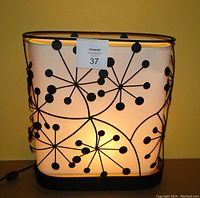 Front view of the modern table lamp lit, showing metal frame pattern on parchment liner.