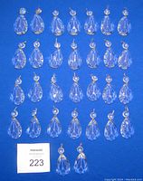 Top view showing 50 clear crystal teardrop chandelier drops arranged in rows on a blue background.