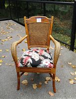 Front view of rattan chair showing woven backrest and tropical floral upholstered seat cushion.