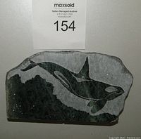 Front view of soapstone carving showing whale design and auction label.