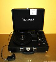 Top view of the Victrola portable record player inside the open black suitcase-style case, showing the turntable, tonearm, control buttons, and power knob.