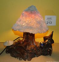 Front view of vintage mushroom gnome lamp illuminated, showing textured mushroom shade and gnome figure on tree stump base.