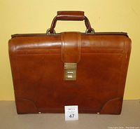 Front view of brown leather briefcase showing combination lock and handle.