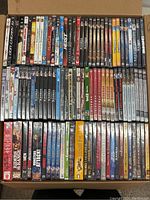 Top-down view of DVDs arranged in box rows showing variety of titles and packaging condition.