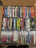 Top-down view of DVDs in a box showing various animated, action, and family movies including The Jungle Book, Curveball, and Wolverine series.