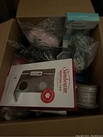 Box open showing multiple items inside including the Sunbeam heating pad box and Proactiv skincare products.