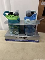 Front view of the two Contigo Kids water bottles in original packaging, showing green and blue lids.