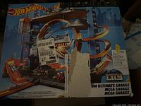 Seal box showing front with torn label and damage but visible artwork of the multi-level garage playset and shark motif