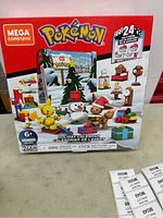 Front of the Mega Construx Pokémon Holiday Calendar box showing age 6+, 246 pieces, and buildable figures including Pikachu, Eevee, snowman, and holiday items.