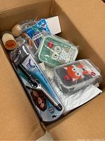 Top view inside box showing eyelash curler, colored pencils, animal-themed containers, and other assorted packaged items.