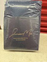 Front view of the SlumberMee navy blue fleece plush men's robe in original sealed packaging. Branding visible in gold text.